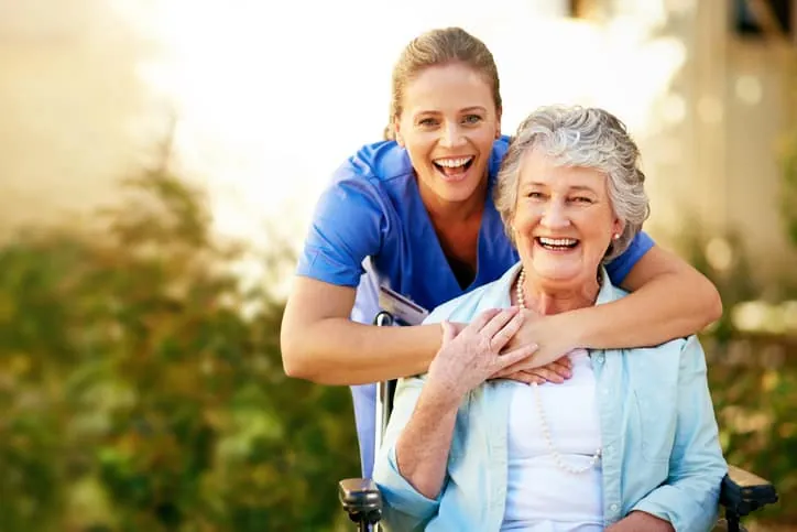 Caregiver and senior woman smiling together outdoors