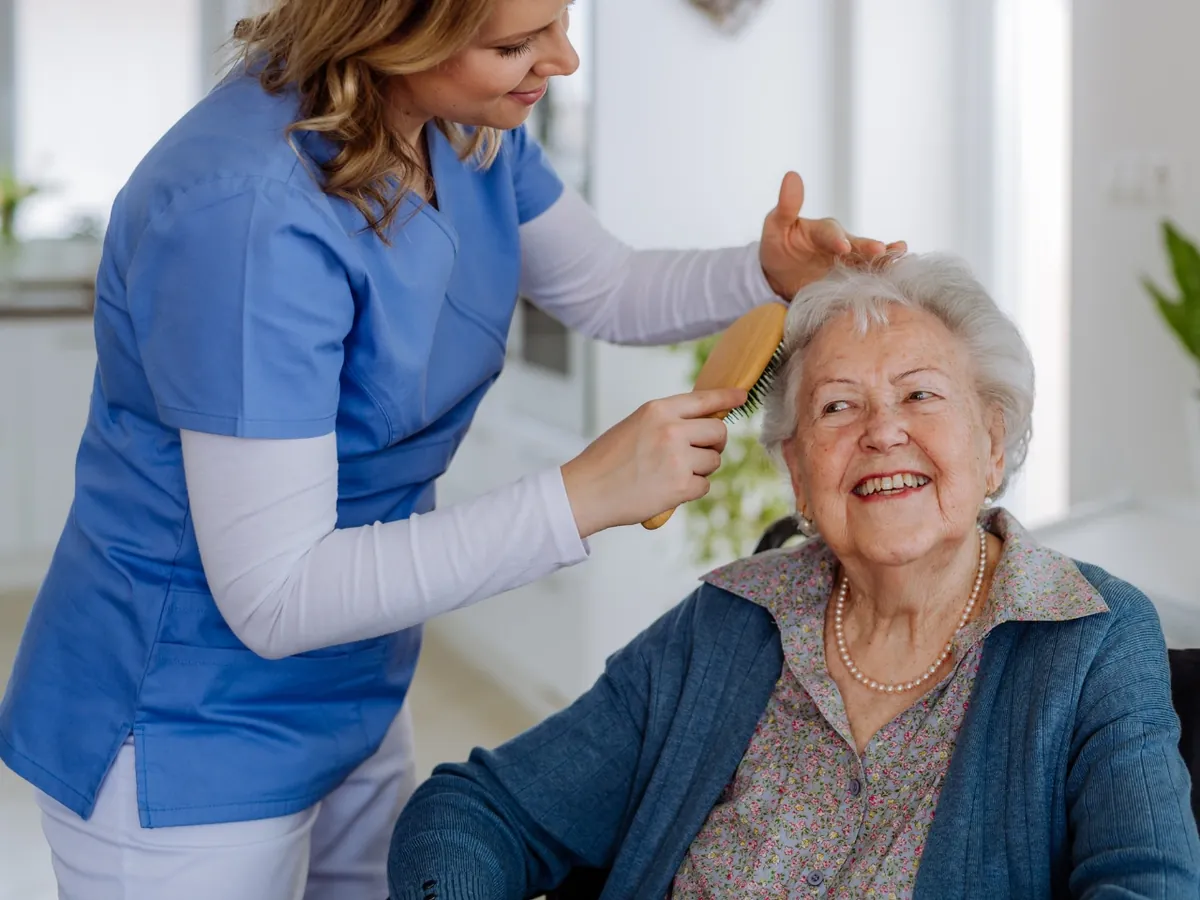 Caregiver gently brushing a senior woman's hair