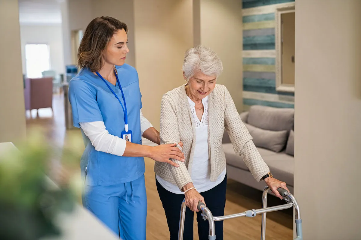 Caregiver steadying a senior woman using a walker at home