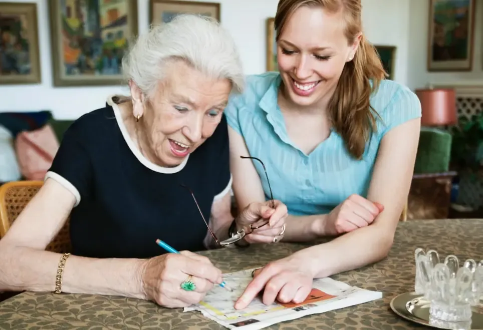 Caregiver helping a senior woman with a crossword puzzle