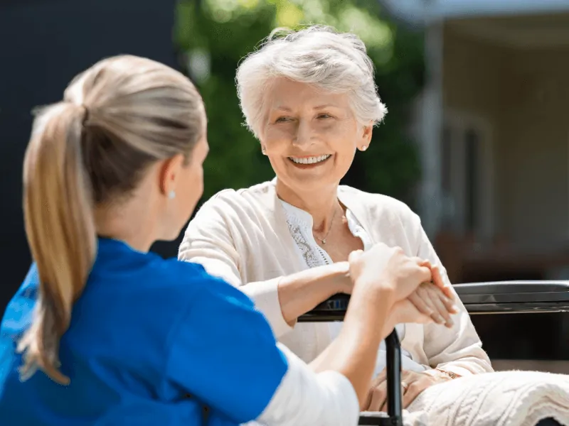 Caregiver holding hands with a senior woman outdoors