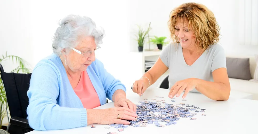 Caregiver doing a jigsaw puzzle with a senior woman
