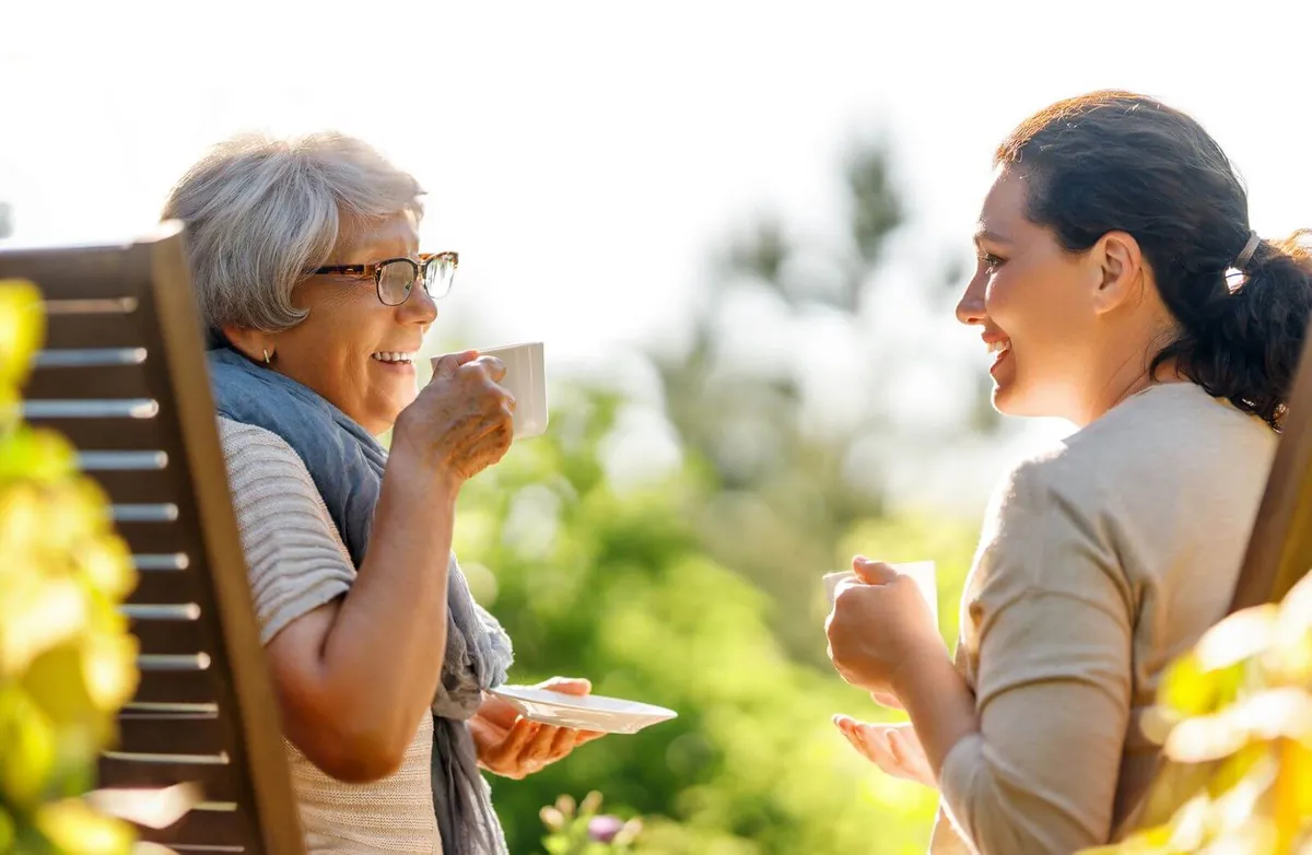 Senior woman and a younger woman having coffee outside